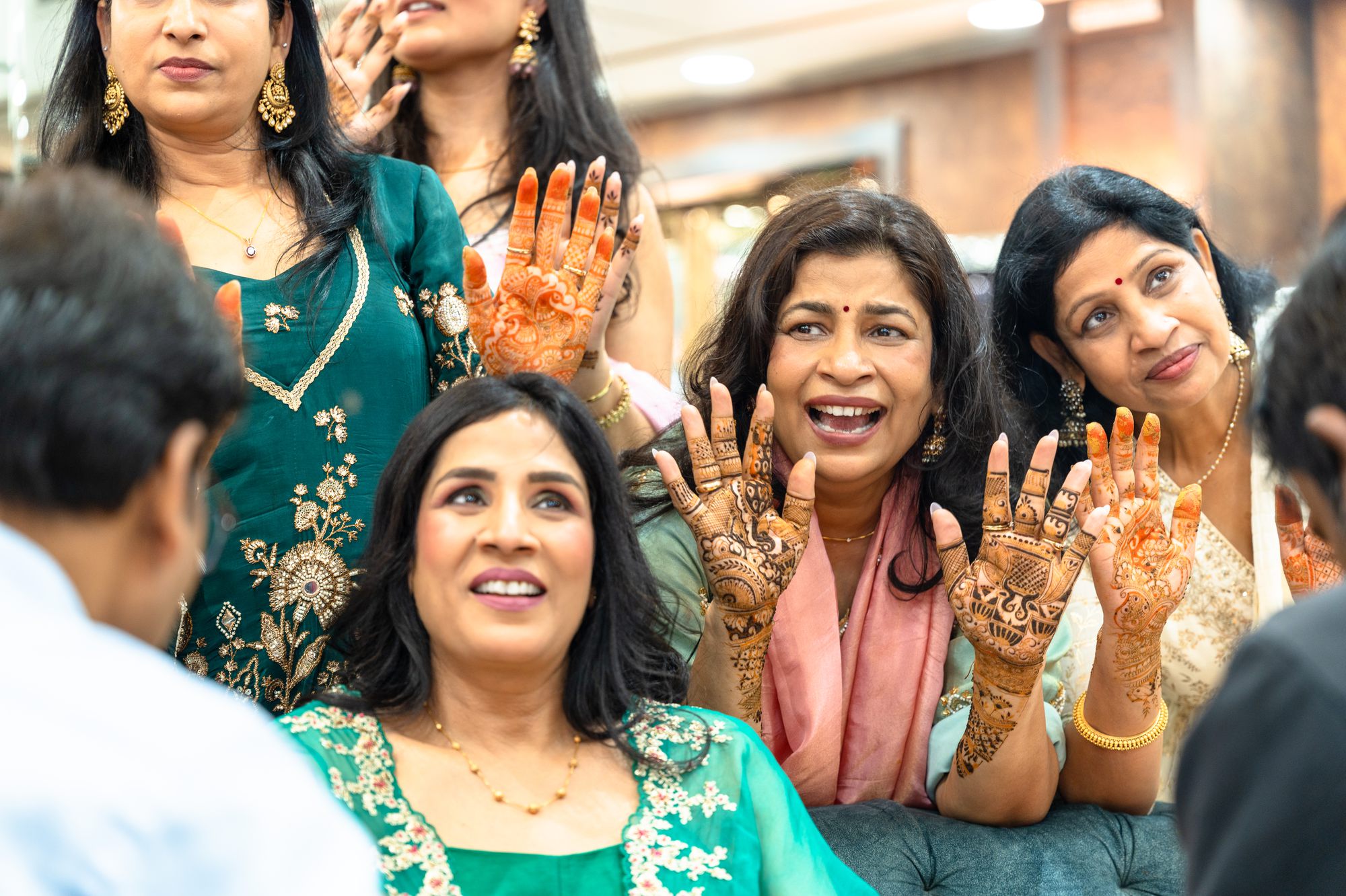 Guests laughing and showing their mehendi at a wedding celebration