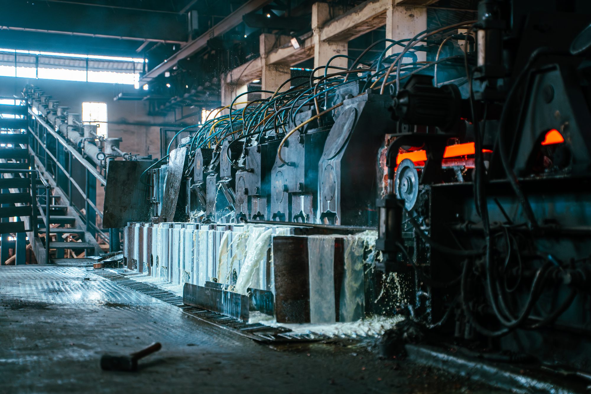 A red-hot copper bar running the length of a rolling mill